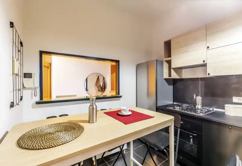Cuisine moderne et compacte avec un bar en bois, plaque de cuisson et réfrigérateur. Agencement lumineux et fonctionnel, parfait pour un court séjour ou un appartement urbain.