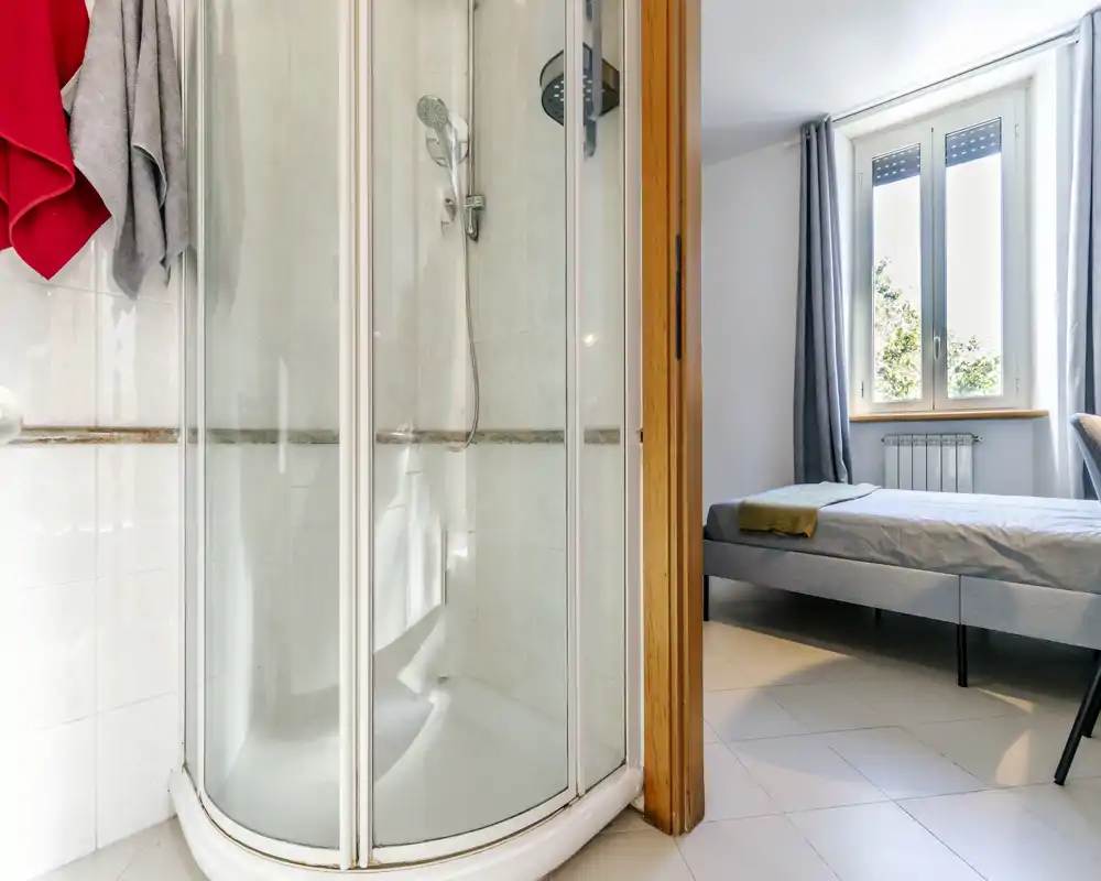Dormitorio sencillo y luminoso con cama doble visible junto a la ventana y ropa de cama neutra — luz natural abundante y decoración moderna y sencilla.