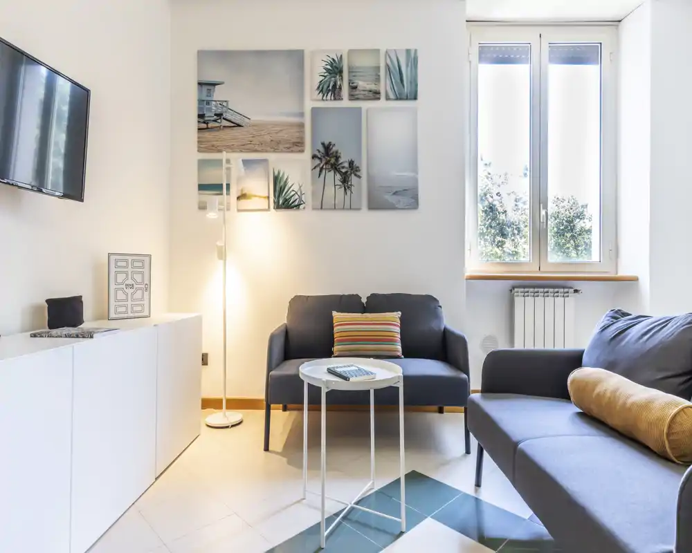 Sala de estar luminosa y con estilo, con dos sofás cómodos, cuadros decorativos y una mesita — ideal para relajarse con luz natural.