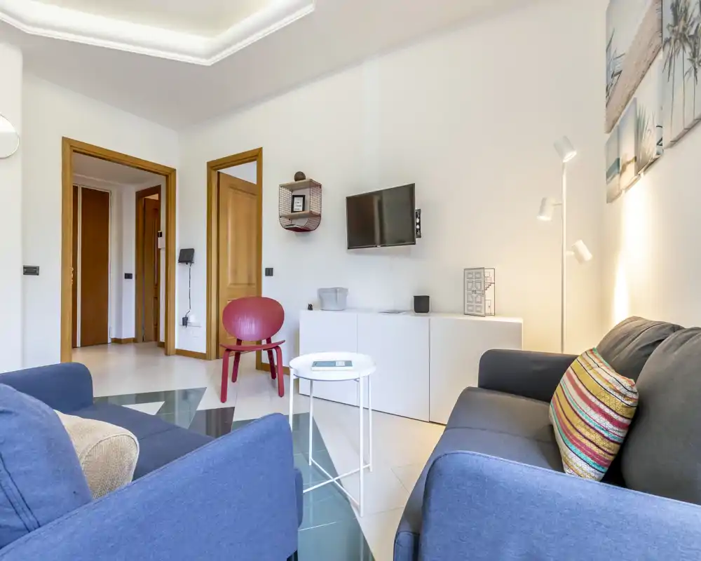Salón luminoso y bien decorado con dos sofás, mesita de centro y TV de pared; decoración contemporánea e iluminación suave que lo hacen acogedor.