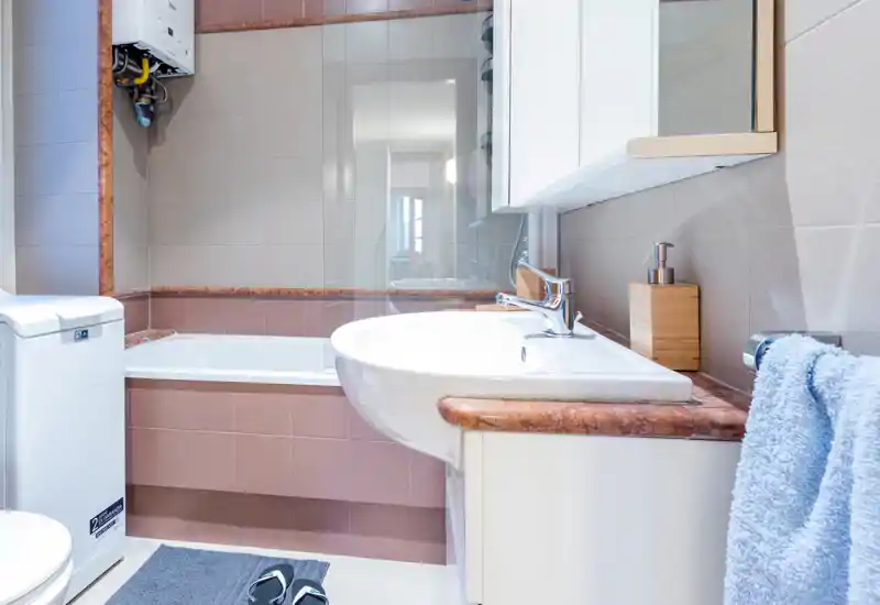Bright, well-lit bathroom with a bathtub, wall-mounted sink and mirrored cabinet; clean tiles and coordinated towels create a neat, modern look.
