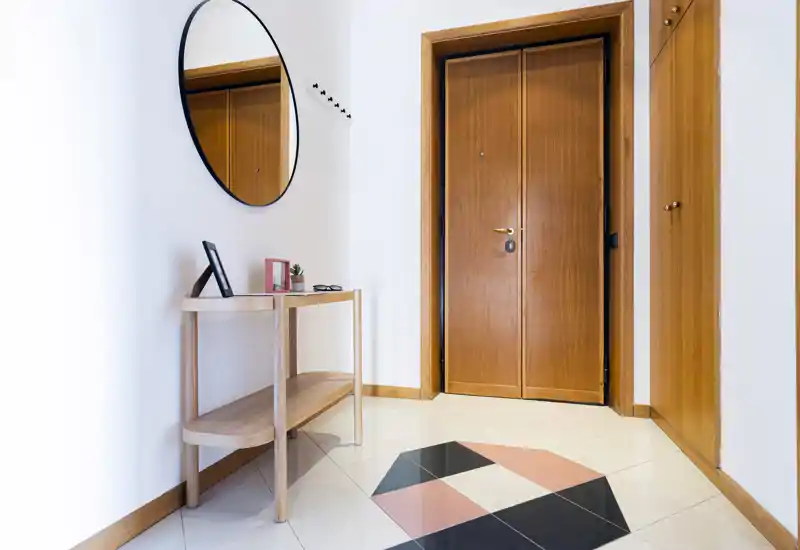Entrée lumineuse et soignée avec porte en bois, miroir décoratif et une console fine — idéale pour une bonne première impression.