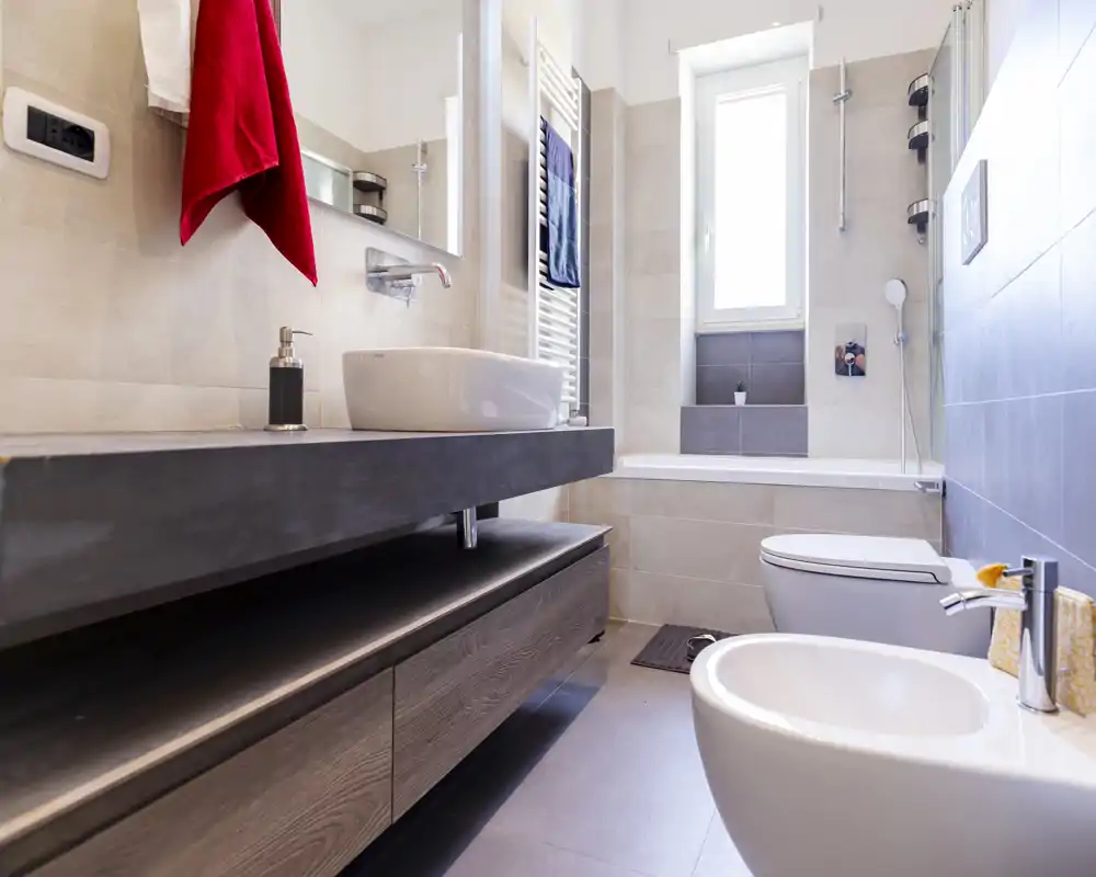 Modern, bright bathroom with bathtub, wall-mounted sink, bidet and toilet; contemporary tiles and clean finishes.