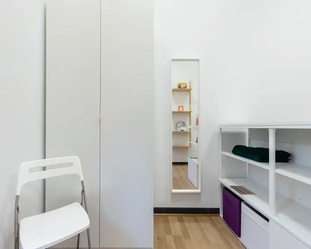 Piccolo ingresso/angolo guardaroba funzionale con armadio alto, specchio a tutta altezza e scaffali aperti — essenziale, luminoso e ordinato.