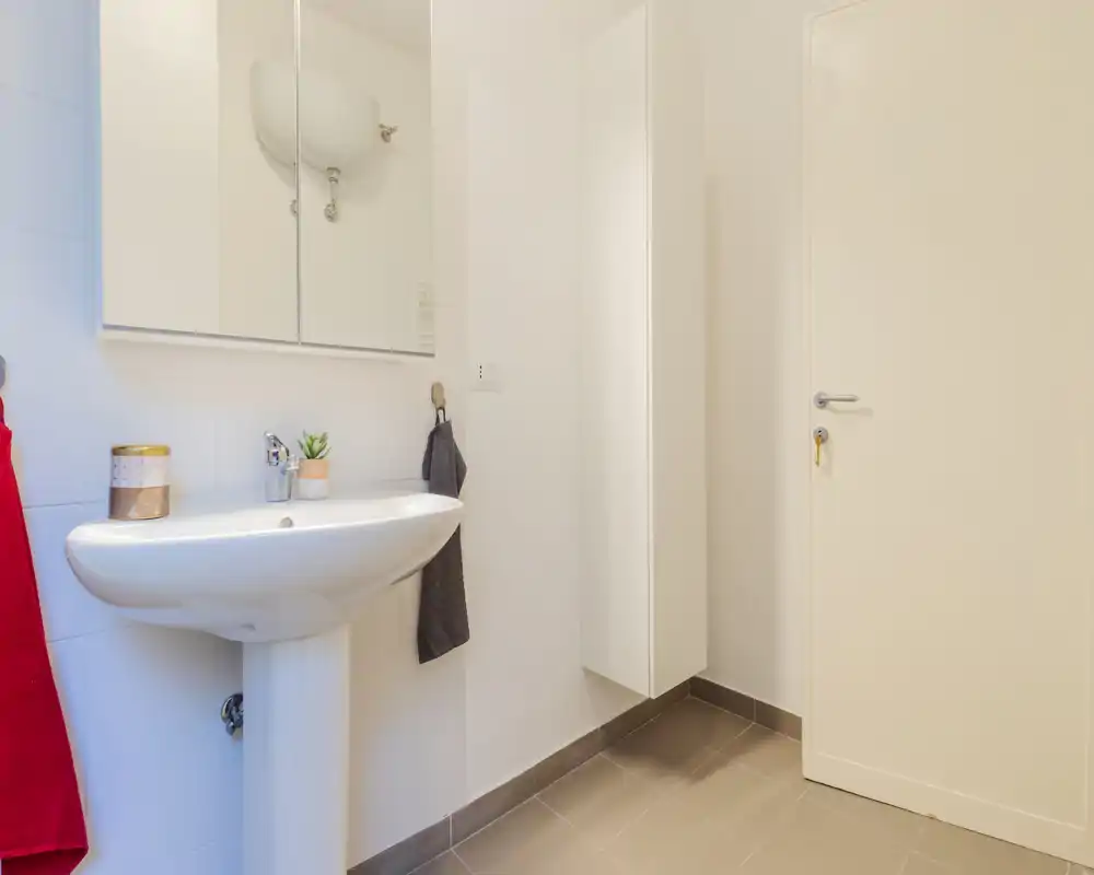 Cuarto de baño moderno y luminoso con lavabo exento, armario con espejo y mueble de pared — diseño limpio y minimalista ideal para alquileres vacacionales.