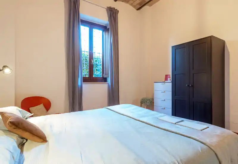 Dormitorio luminoso y ordenado con cama amplia, ropa de cama suave, armario y luz natural desde la ventana — ambiente tranquilo y acogedor para el anuncio.