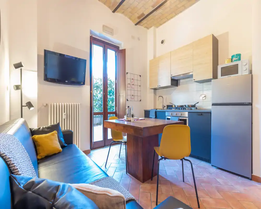 Acogedora zona de estar de estilo con cocina abierta compacta, mesa de madera y sofá cómodo — ideal para una estancia urbana agradable.