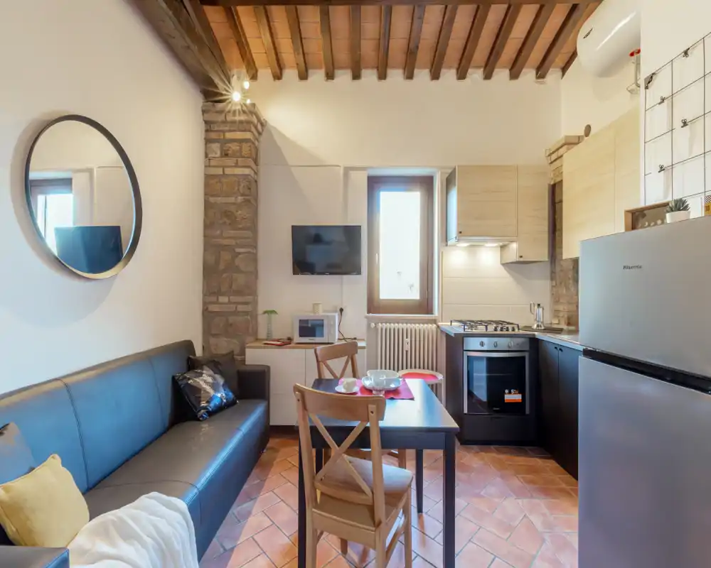 Espace de vie lumineux et chaleureux avec kitchenette compacte, table à manger et canapé confortable sous un plafond en bois rustique — parfait pour courts séjours.