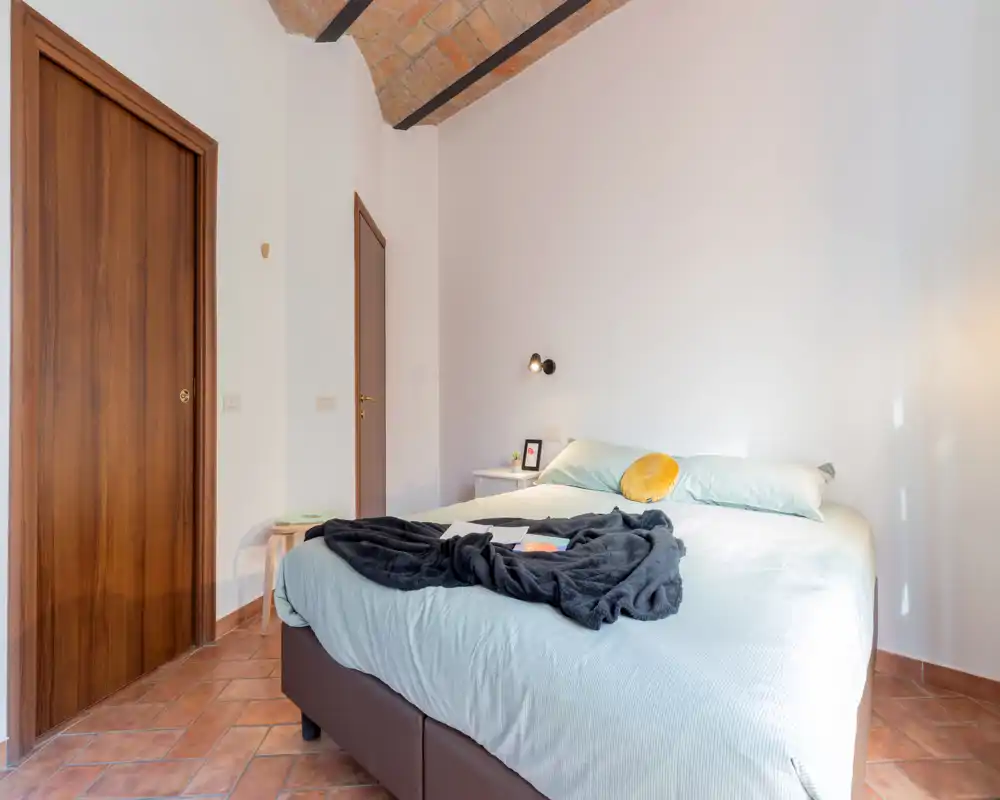 Chambre lumineuse et accueillante avec lit double, linge de lit doux, coussin décoratif et jolie voûte en briques apparentes.