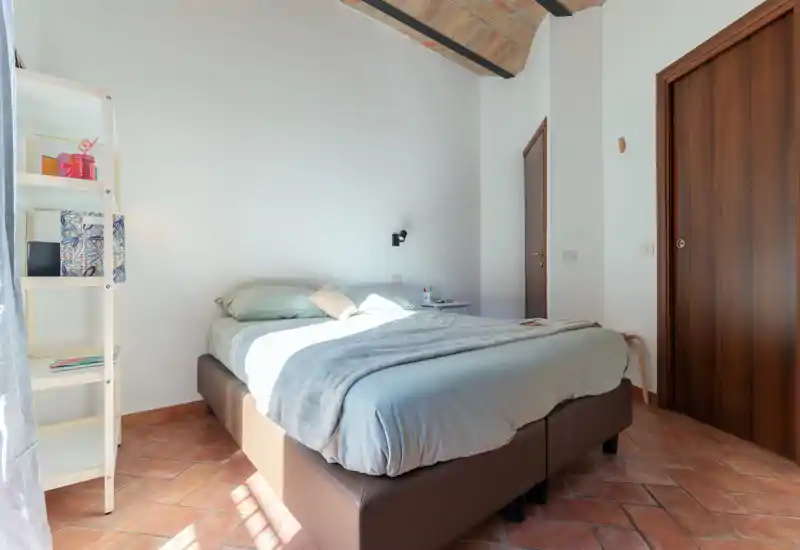 Dormitorio luminoso y aireado con una cama doble cómoda, ropa de cama suave y suelo de terracota bajo un encantador techo abovedado — ideal para una estancia tranquila.