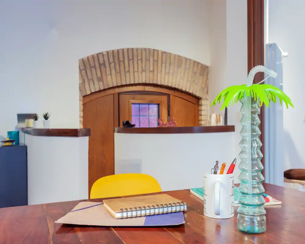 Mesa de comedor/trabajo acogedora con tablero de madera, silla brillante y elementos decorativos; ideal para comidas informales o teletrabajo en un rincón luminoso.