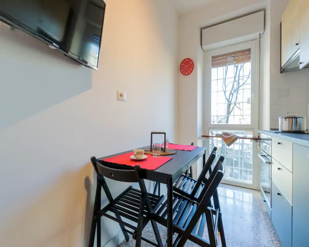 Compact, sunlit kitchen with a small dining table for two-four people, modern cabinets and a window providing natural light — ideal for cozy breakfasts.