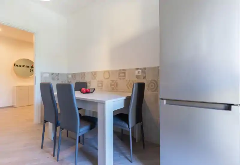 Coin repas de cuisine compact avec table en bois clair, quatre chaises grises modernes et crédence carrelée à motifs ; lumineux, propre et bien stylé pour des repas décontractés.