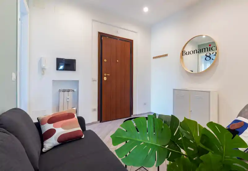 Entrée accueillante avec porte d'entrée en bois, miroir et petit meuble de rangement, un canapé et des plantes décoratives offrant une première impression chaleureuse.