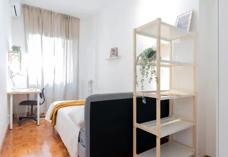 Bright, minimalist bedroom with a comfortable double bed, light textiles and a small desk by the window—ideal for a calm, airy stay.