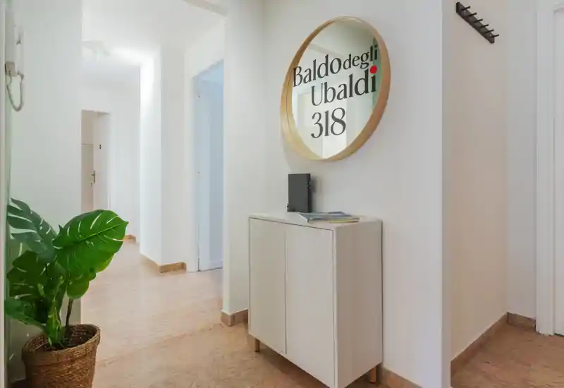 Bright, welcoming entrance hallway with a decorative round mirror, slim console cabinet and potted plant — clean modern styling and natural light.