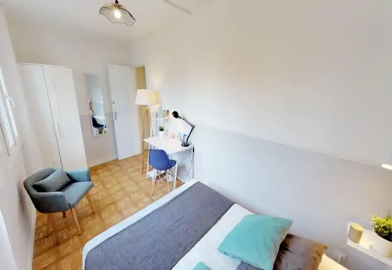 Bright, neatly staged bedroom with a comfortable double bed, cozy textiles and a desk by the wall — ideal for both rest and a small workspace.