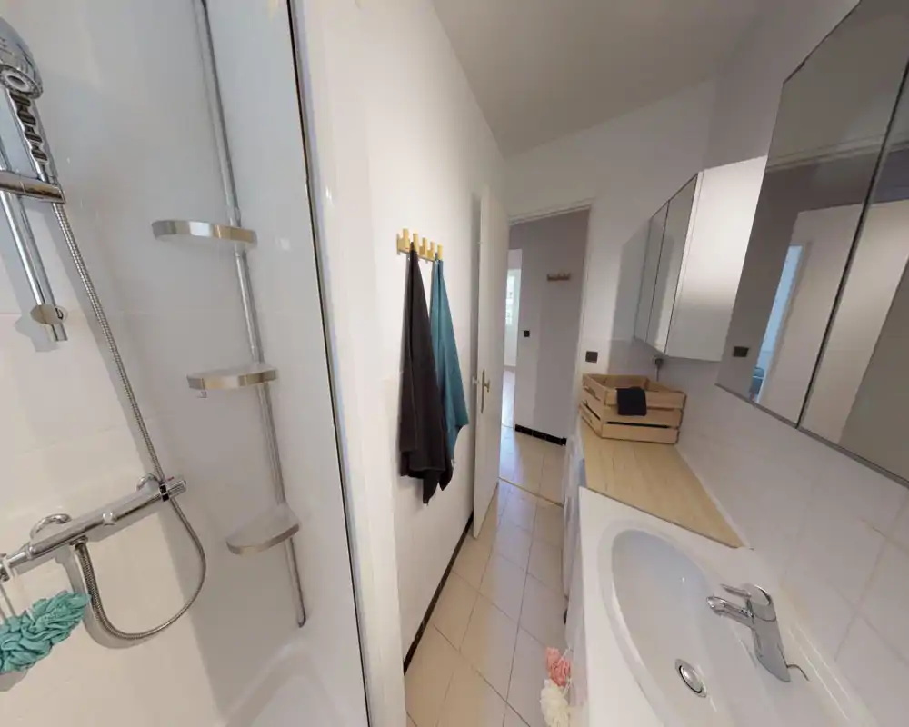 Bright, modern bathroom with a sink, mirrored cabinets and a shower. Clean tile surfaces and wooden countertop details create a fresh, functional feel.