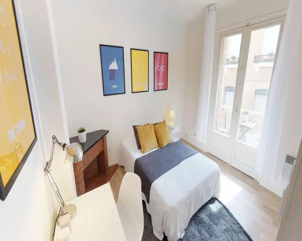 Bright attic bedroom with a double bed, pillows and soft textiles; white walls and angled ceiling let in natural light, creating an airy, welcoming space.