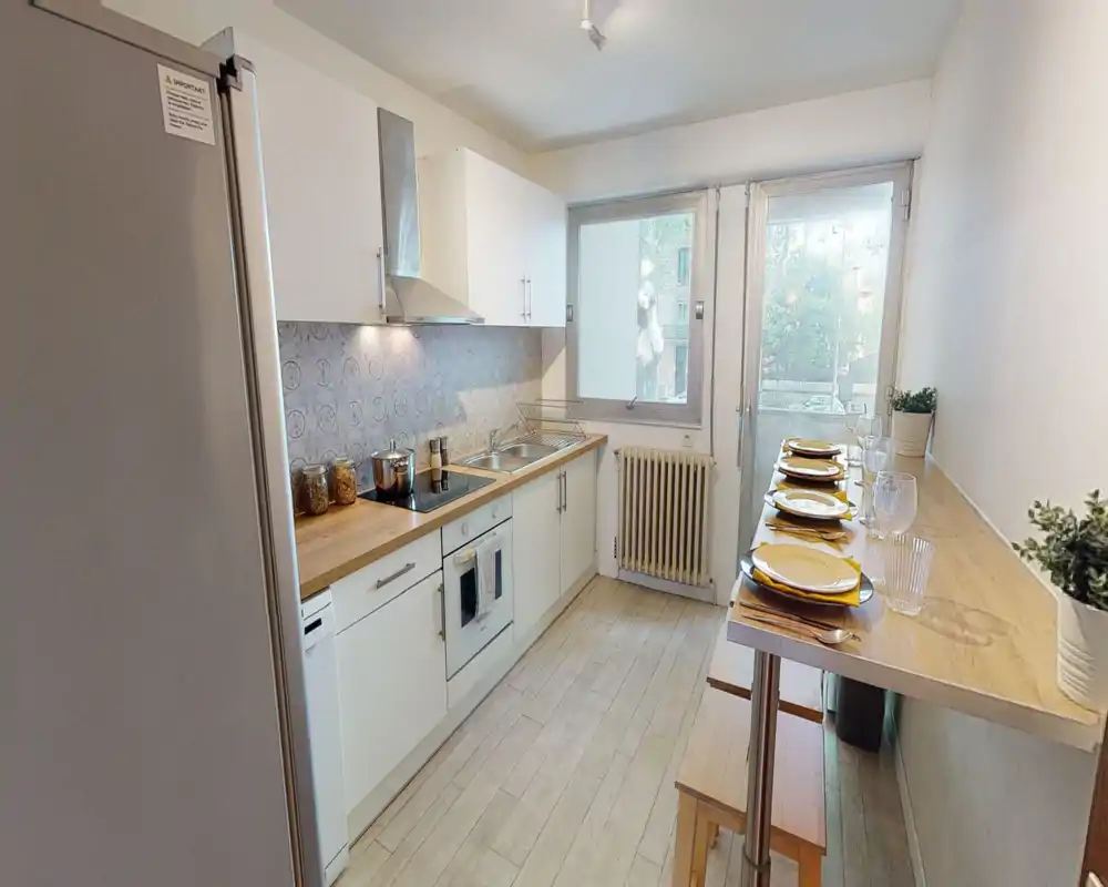 Bright, modern galley kitchen with wooden countertops, white cabinets, integrated appliances and a breakfast bar set for four—well-lit and neatly staged for rentals.