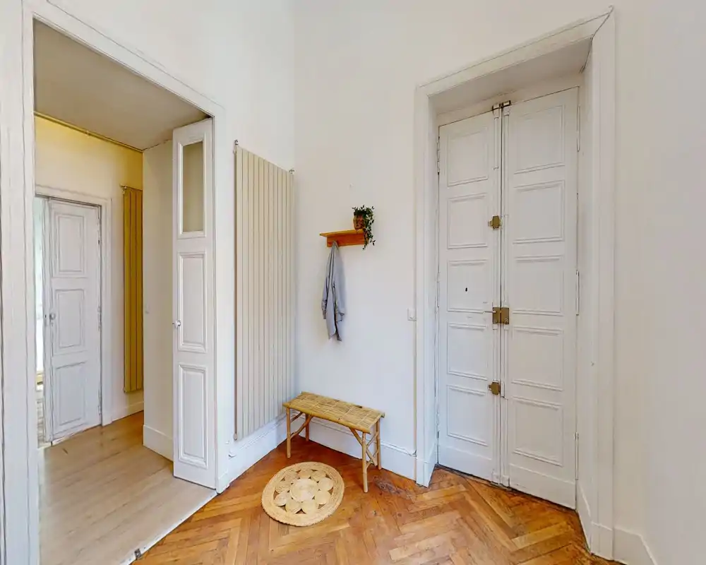 Entrée lumineuse et accueillante avec parquet en point de Hongrie, un banc et un tapis décoratif — première impression pratique et soignée.