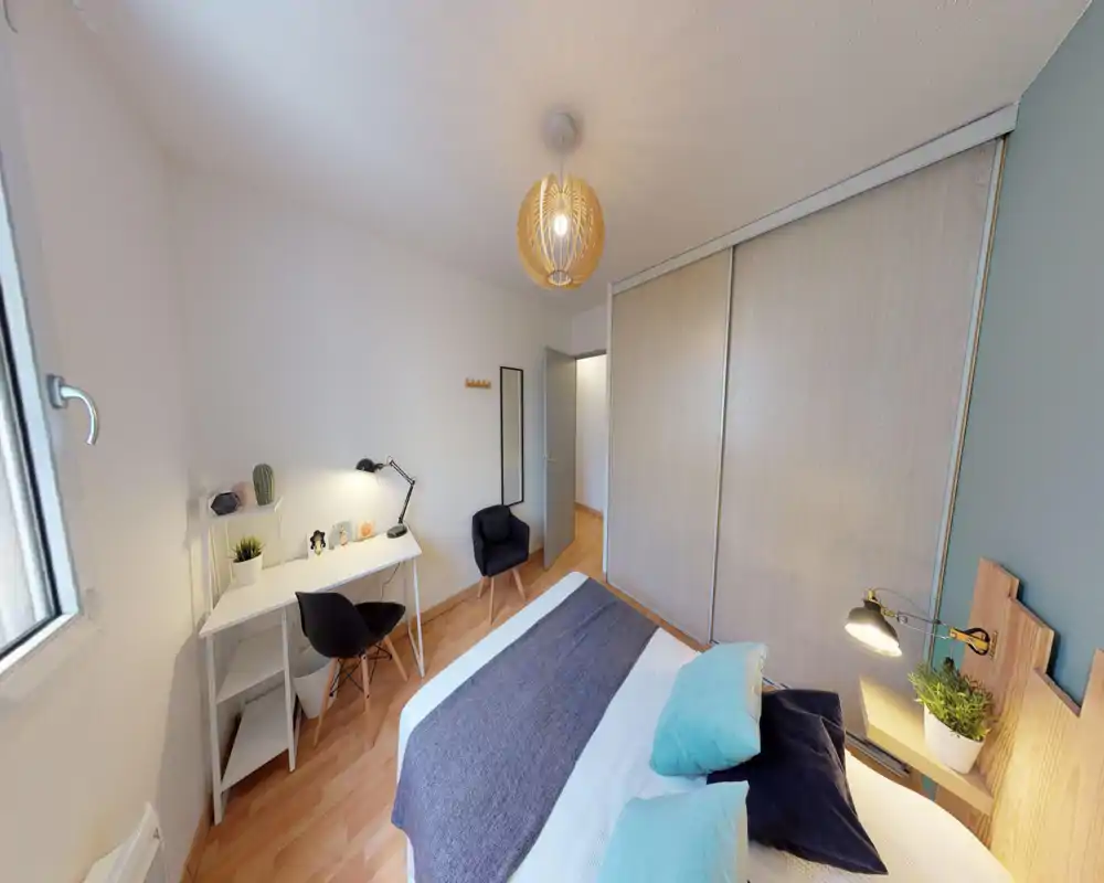 Camera da letto luminosa e ben allestita con letto doppio, lampada da comodino e armadio scorrevole; una scrivania vicino alla finestra la rende adatta anche al lavoro.