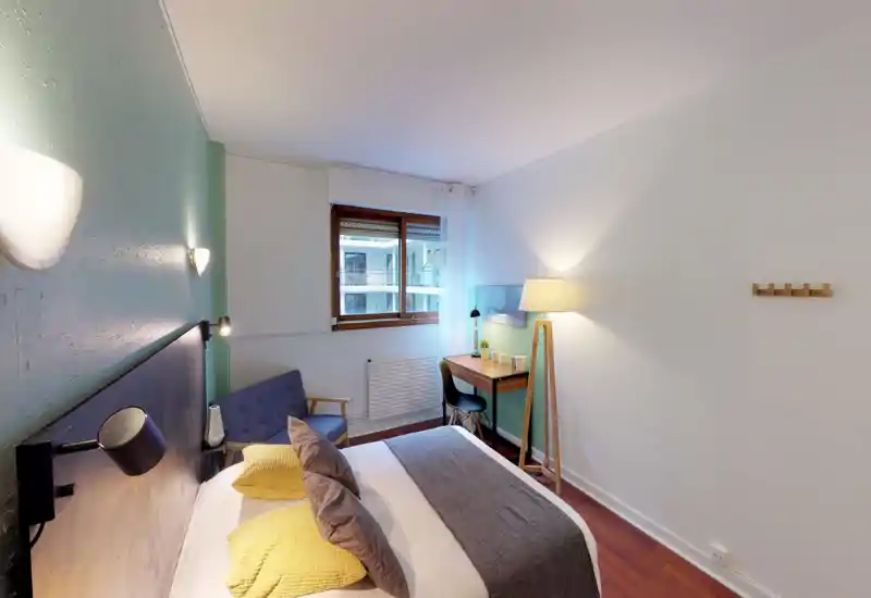 Bright, well-staged bedroom with a comfortable double bed, soft textiles and a small desk by the window — ideal for both rest and light work.