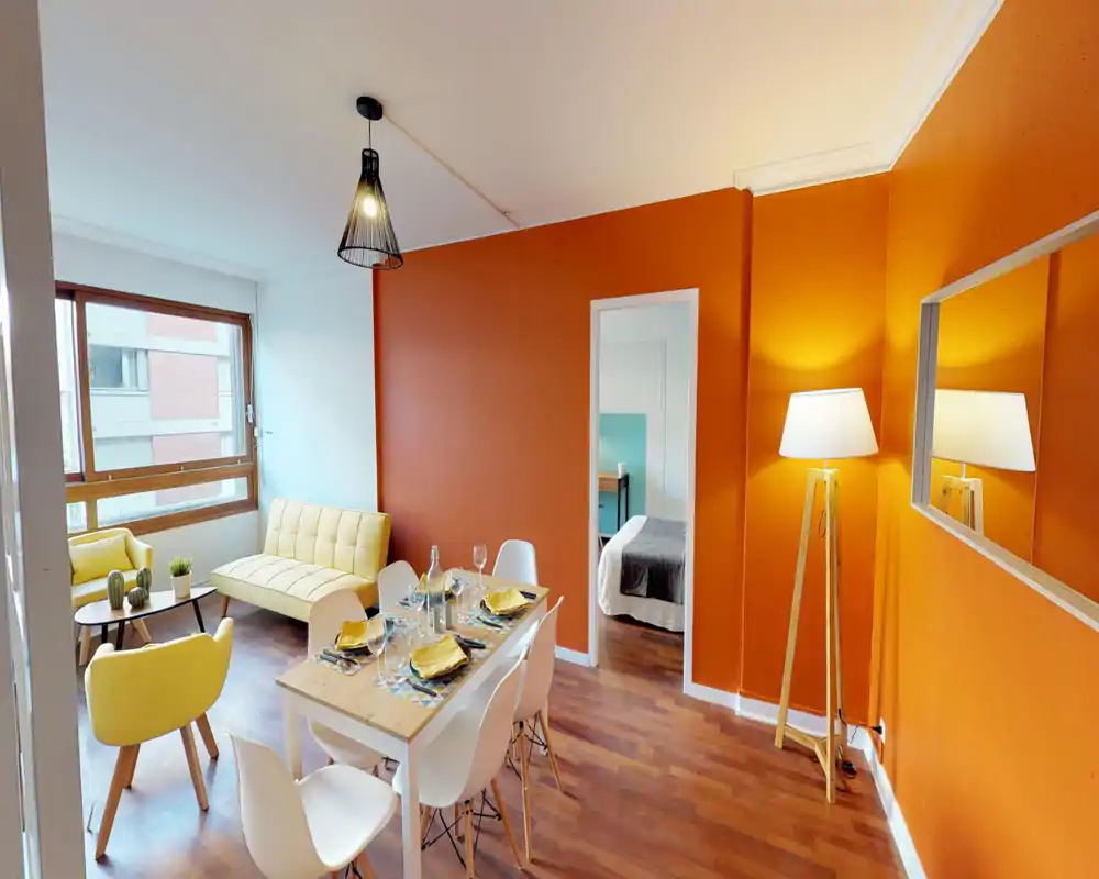 Bright, stylish living and dining area with yellow seating, a set dining table and warm orange accent walls. Large window offers natural light and contemporary decor creates a welcoming atmosphere.