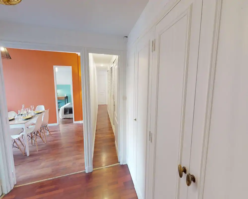 Bright hallway/entrance with built-in storage and wood floors leading to a dining area and bedroom; clean, well-lit corridor ideal for circulation.