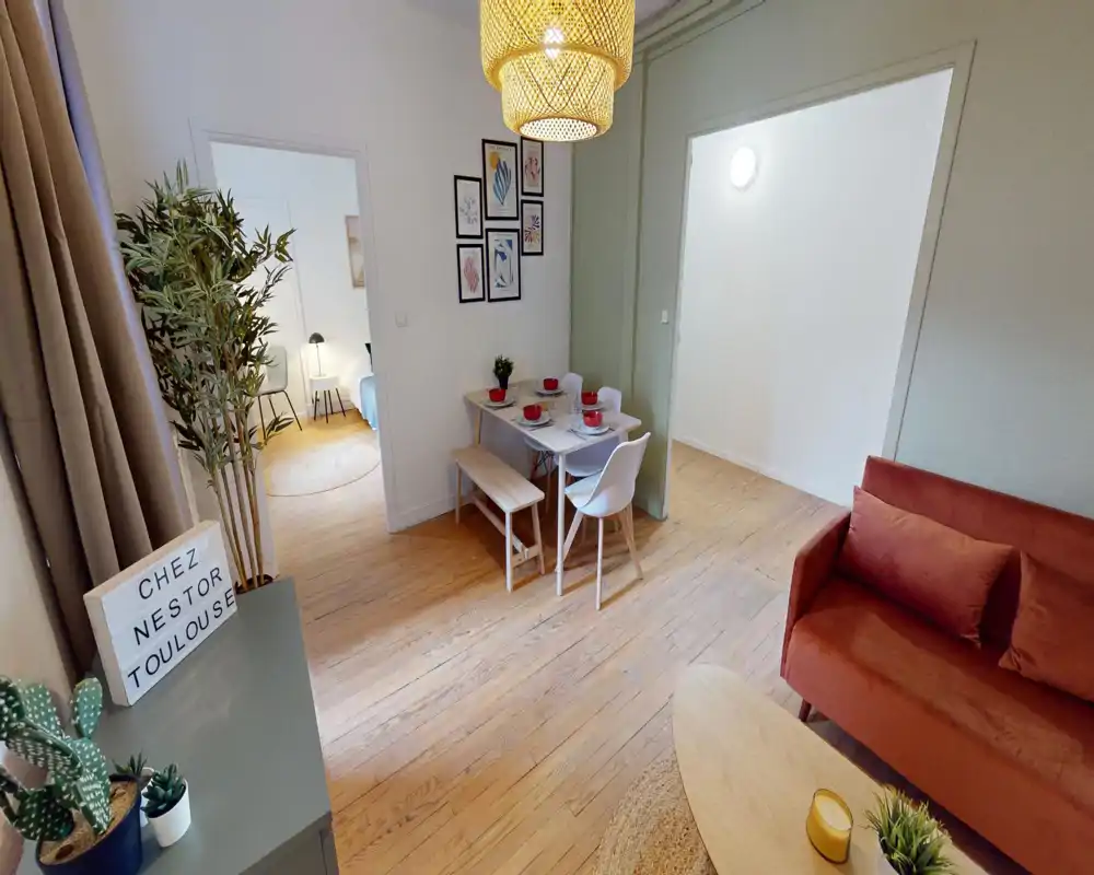 Zona giorno luminosa e di stile con divano color ruggine, tavolino e piccolo set da pranzo — ottima luce naturale e decorazioni curate, ideale per annunci.