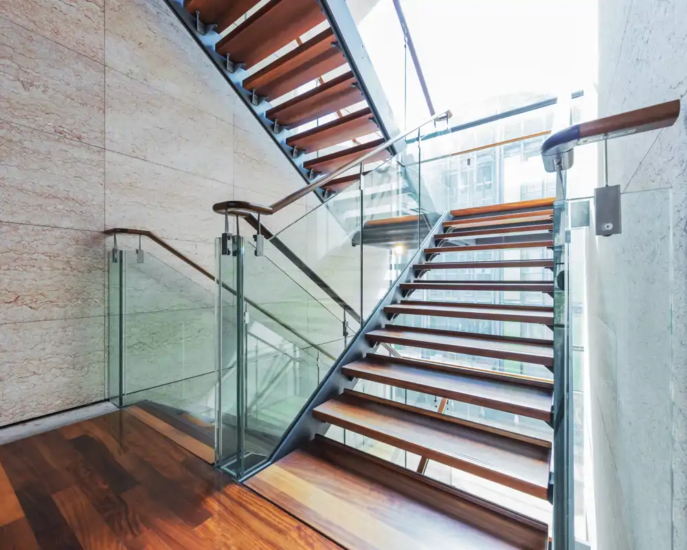 Contemporary entrance/stairwell with wooden floating steps, glass balustrades and natural stone walls. Bright, modern design ideal for a stylish apartment or office lobby.