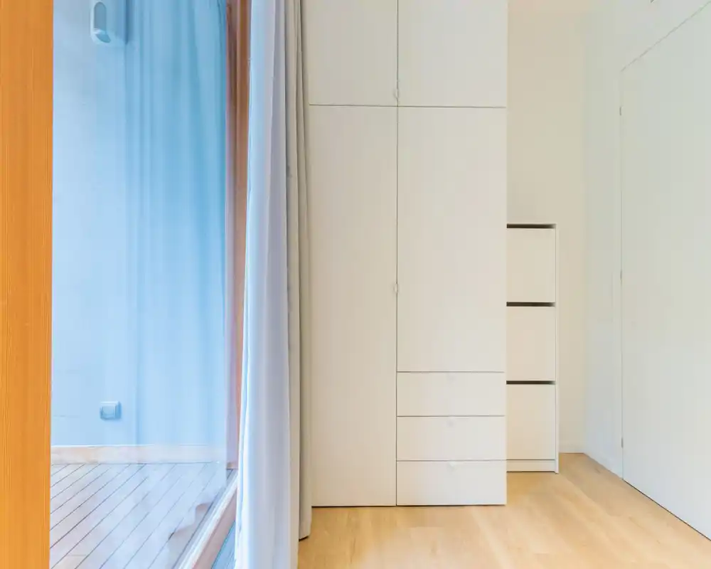 Bright, minimal entry area with built-in storage and a door leading to an outdoor deck; clean lines and natural wood flooring create a tidy first impression.