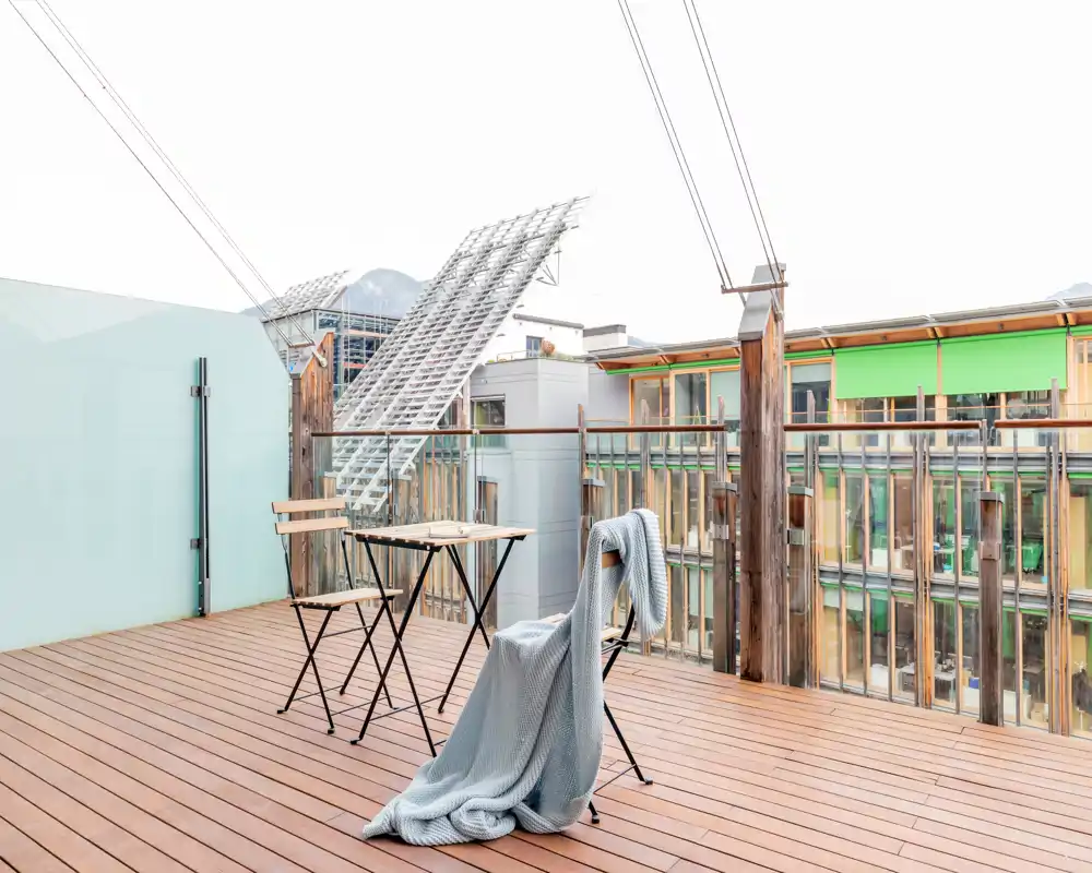 Sunny private terrace with wooden decking, a small table and folding chairs — ideal for morning coffee or relaxing outdoors.