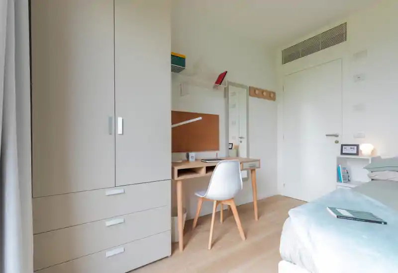 Bright, modern bedroom with a tidy single bed, compact desk and wardrobe — ideal for a student or single occupant.