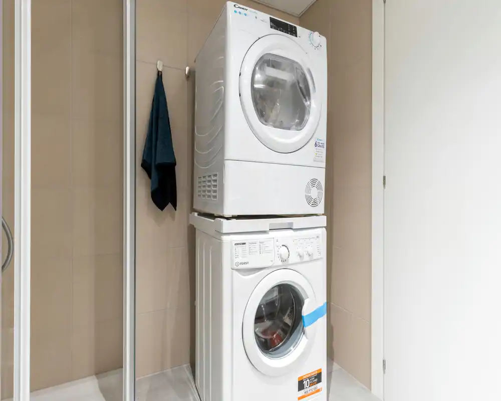 Compact stacked washer and dryer in a small tiled utility alcove, ideal for on-site laundry in the apartment.