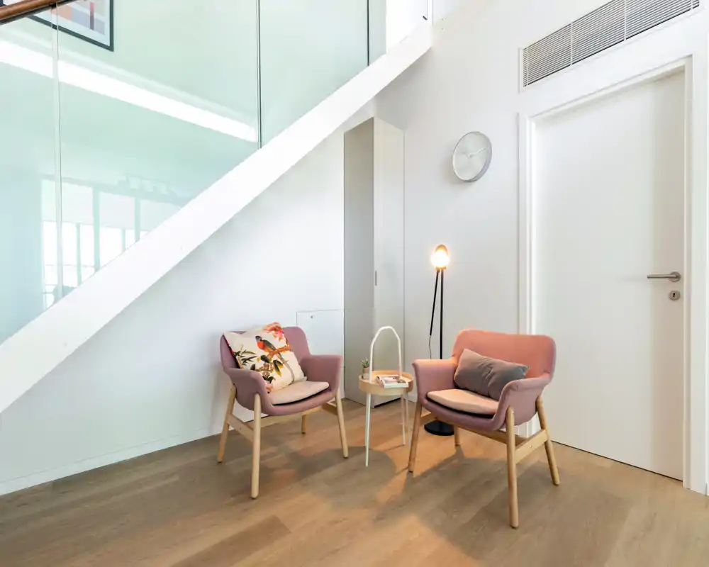 Bright, minimal living nook with two comfortable armchairs, a small side table and a floor lamp — ideal for reading or relaxing in a modern home.