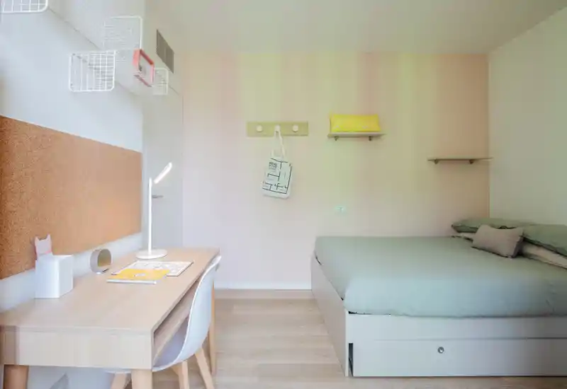 Dormitorio luminoso y minimalista con cama doble cómoda y escritorio ordenado junto a la ventana — tonos pastel y madera natural crean un ambiente moderno y tranquilo.