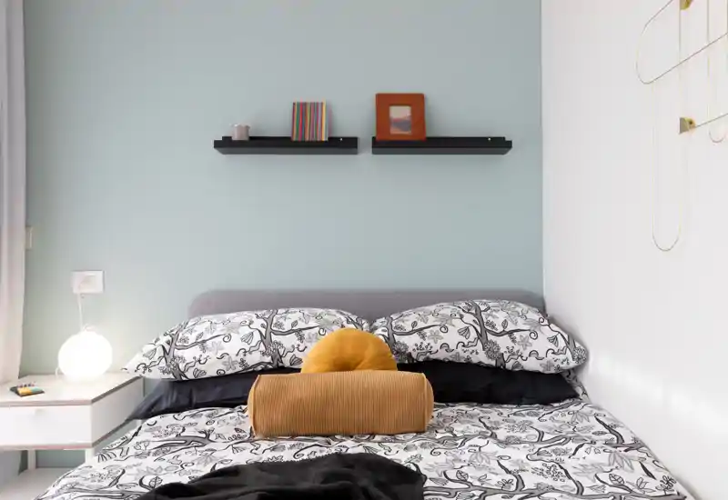 Bright, stylish bedroom with patterned bedding, decorative cushions and a bedside table with soft lamp — ideal for listing photos showcasing a cozy sleeping space.