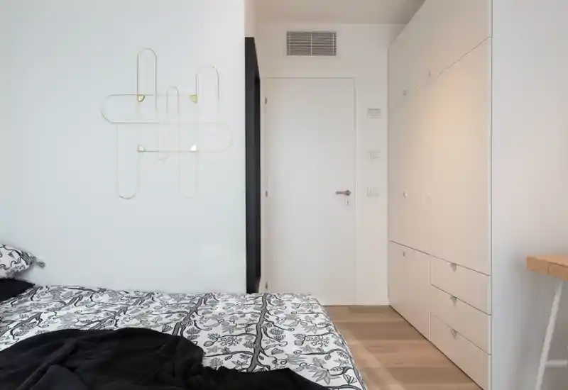 Bright, modern bedroom corner with patterned bed linen, built-in storage and minimal decor offering a calm, contemporary sleeping space.