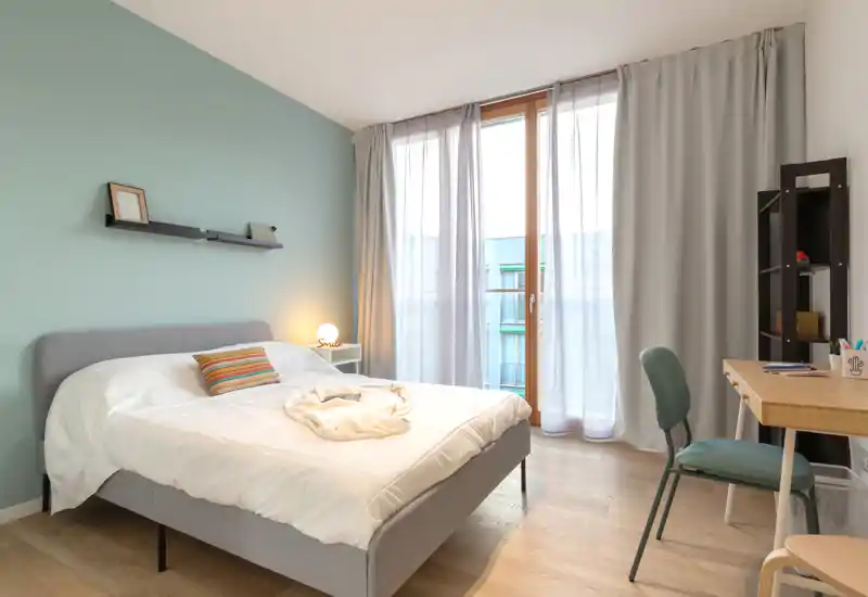 Dormitorio moderno y luminoso con cama doble cómoda, ropa de cama suave y una gran ventana que aporta luz natural — ideal para relajarse.
