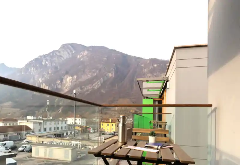 Balcón soleado con pequeña mesa y sillas de madera con vistas al valle y las montañas — ideal para tomar café o leer disfrutando del paisaje.
