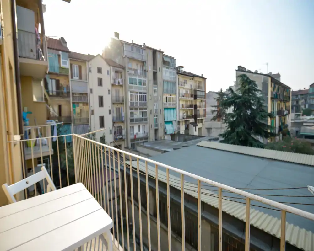 Balcon ensoleillé en ville avec petite table et chaise donnant sur les immeubles voisins — parfait pour un café le matin et se détendre dehors.