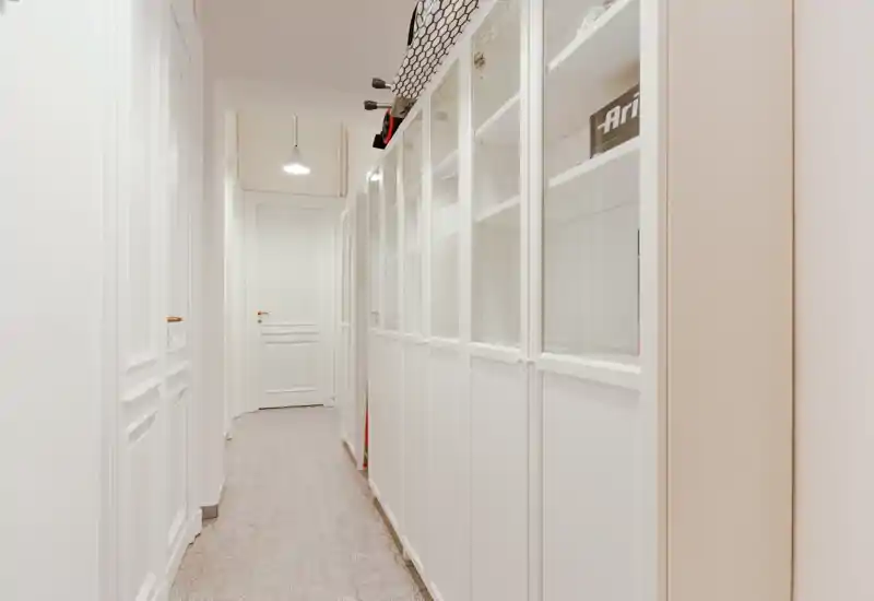 Ingresso/corridoio luminoso e stretto con armadiature bianche incassate e piastrelle dal motivo discreto; stile pulito e minimal con lampada a sospensione.