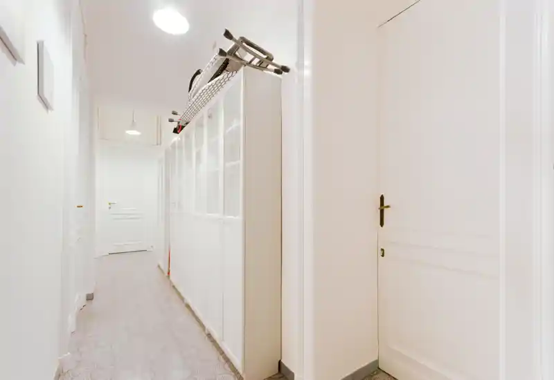 Ingresso/corridoio luminoso e lungo con porte bianche e armadi a vista; pavimento piastrellato e lampade a sospensione creano una buona prima impressione.