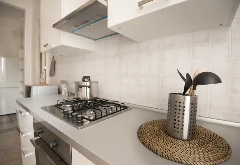 Bright, modern kitchen countertop with a built-in gas hob, stainless pot and utensil holder—clean, minimal styling ideal for apartment listings.