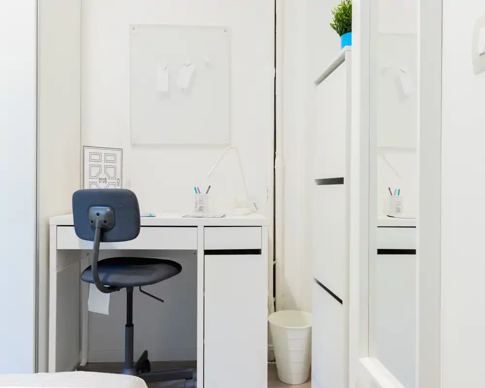 Pequeño rincón de trabajo en la habitación con escritorio blanco, silla giratoria y decoración minimalista y luminosa. Ideal para estudiar o teletrabajar en espacios reducidos.