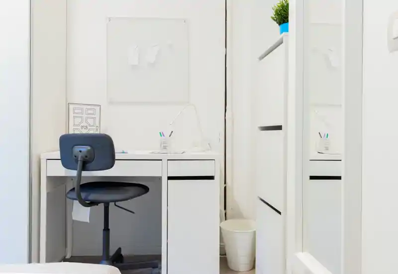 Compact bedroom workspace with a simple white desk, swivel chair and bright, minimalist decor. Ideal for studying or remote work in a small bedroom.