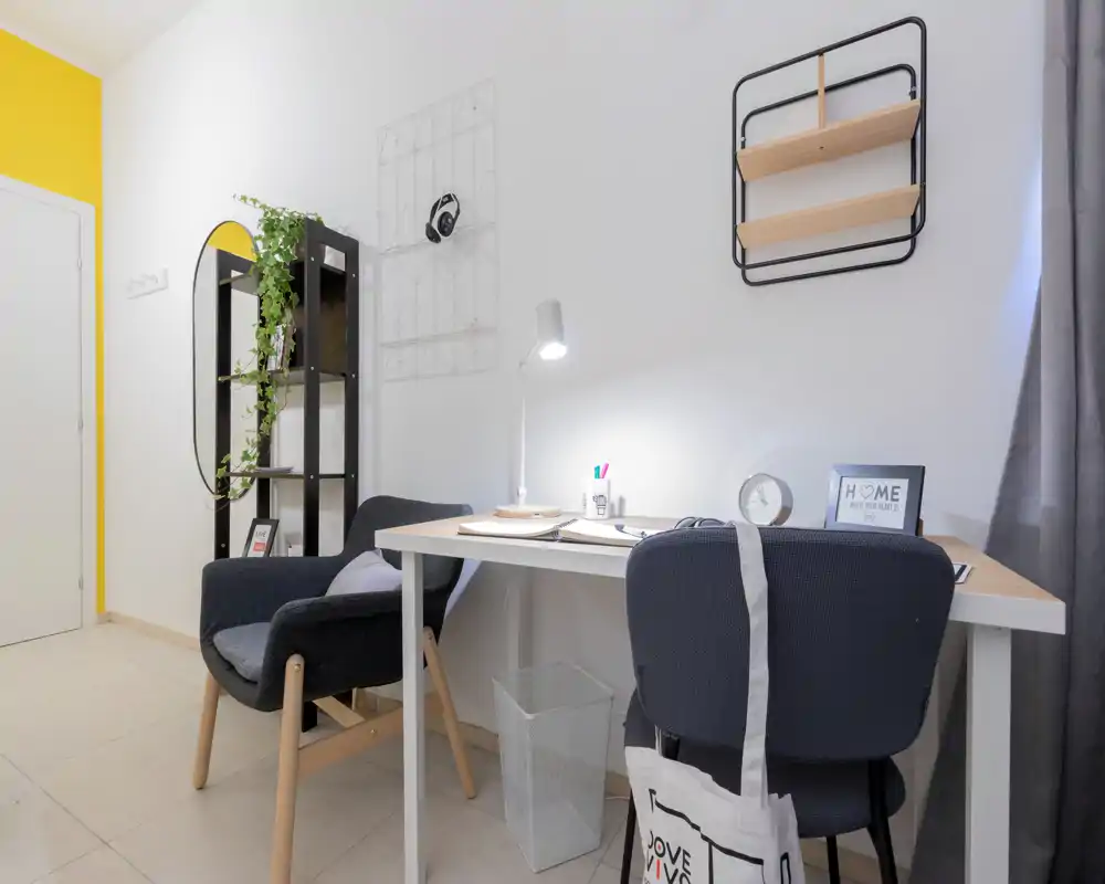 Bright, modern living corner with a work desk and a comfortable armchair, styled with plants, shelving and soft textiles for a welcoming feel.