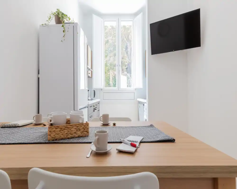 Cuisine lumineuse et minimaliste avec bar en bois, service à thé et lumière naturelle provenant d'une grande fenêtre — style épuré, parfait pour les locations courte durée.