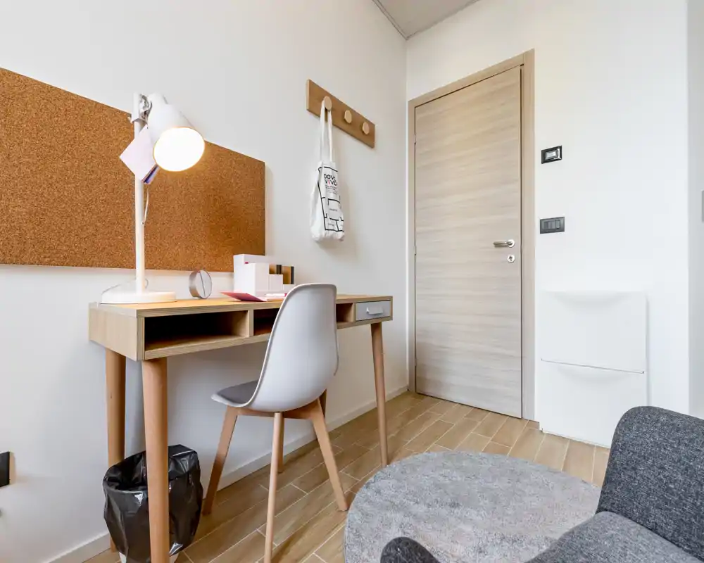 Petit espace de travail élégant avec bureau en bois, chaise ergonomique, panneau en liège et sol en bois clair — idéal pour étudier ou travailler au calme.